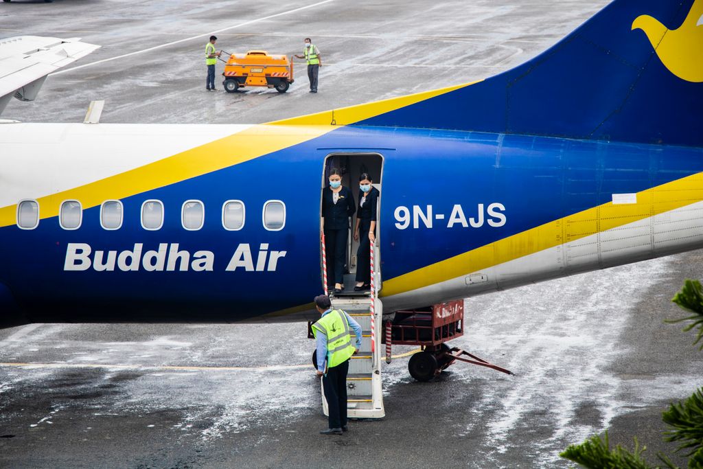 Buddha Airplane with crew members standing at Pokhara Airport entrance, Nepal.